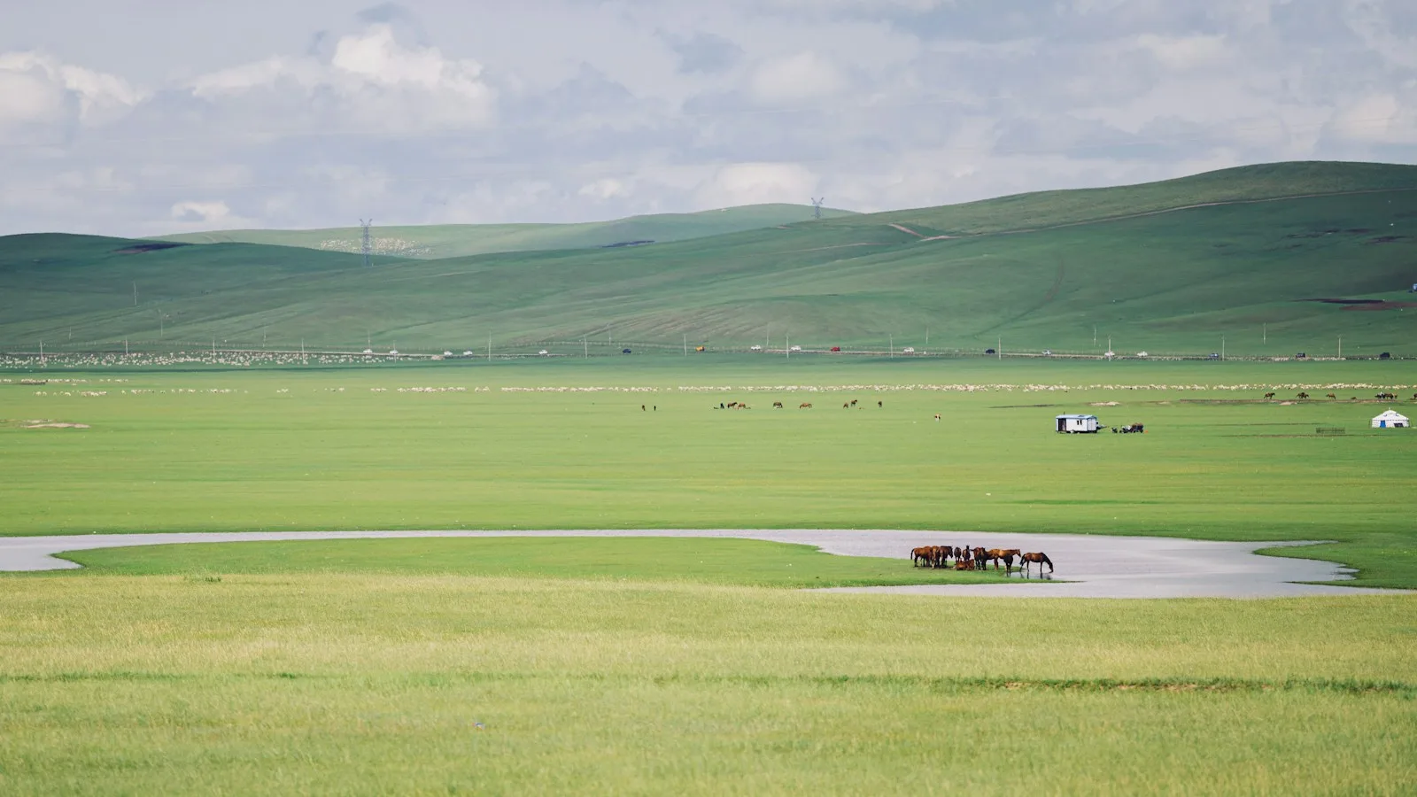 Piste de terre traversant la steppe mongole avec un 4x4 en arrière-plan