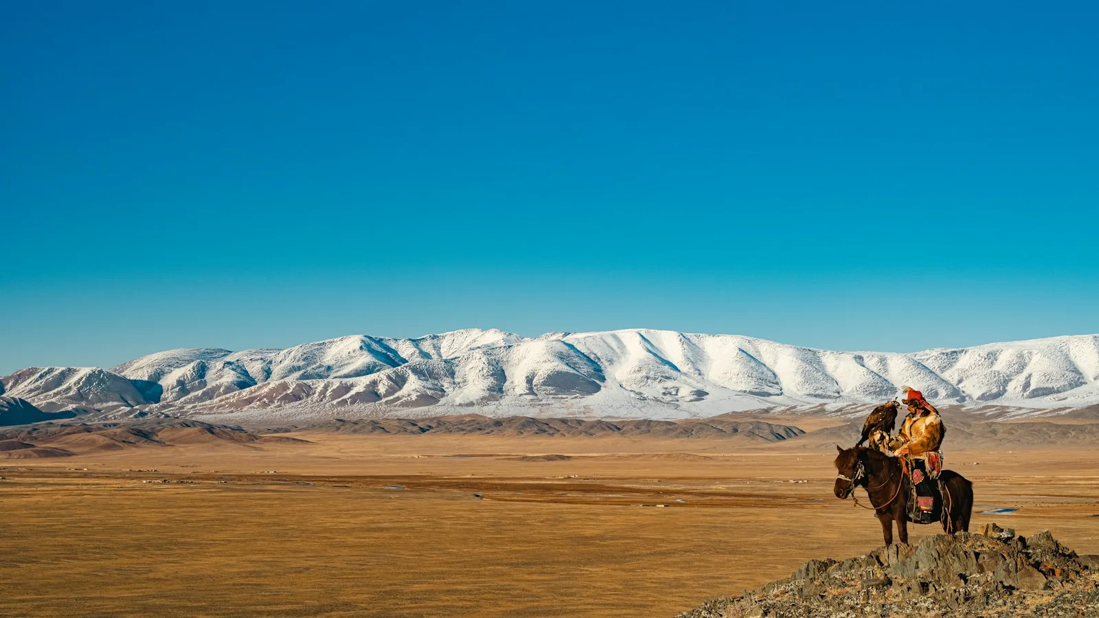 Cavalier mongol surplombant les steppes et montagnes enneigées lors d'un circuit guidé